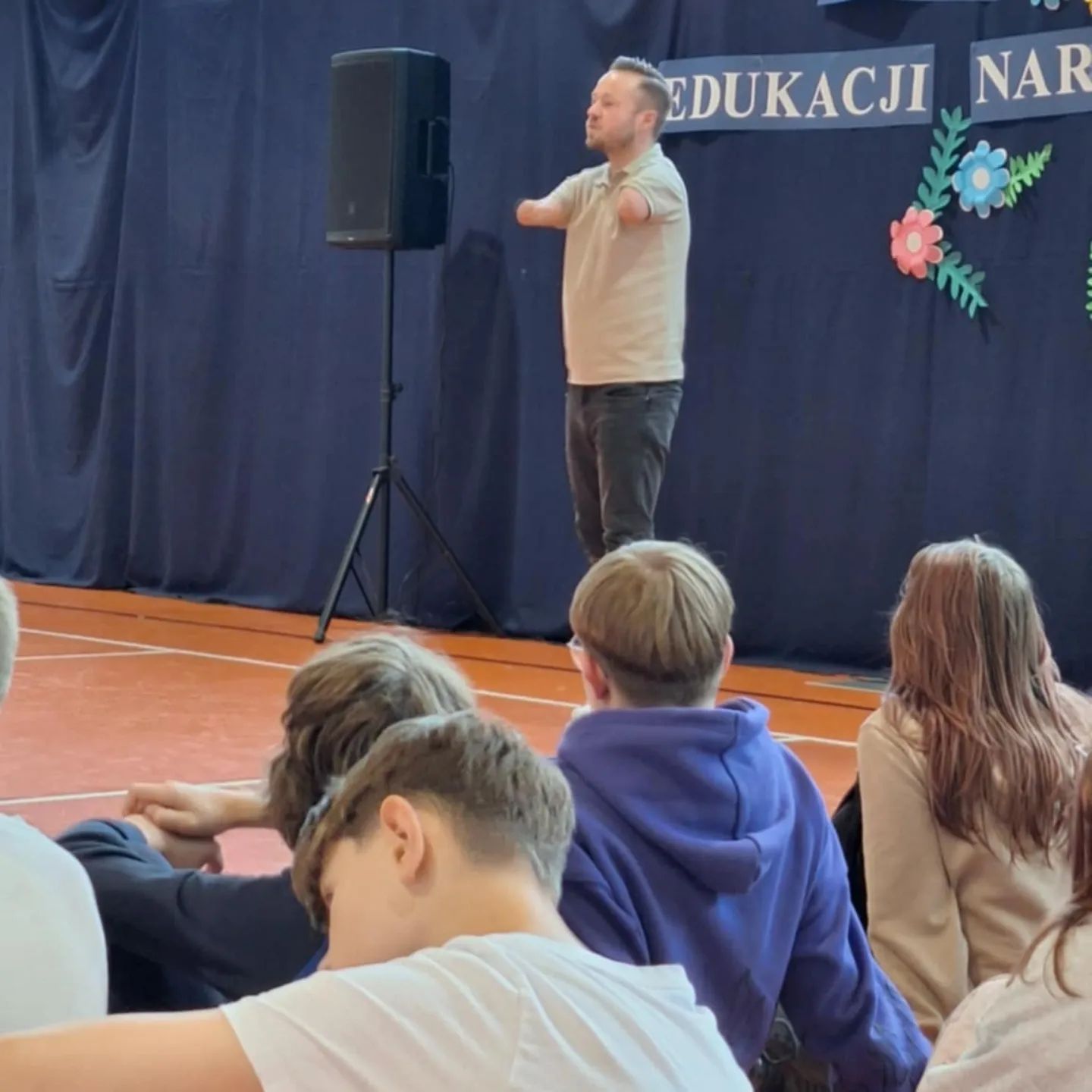 Mariusz Kędzierski przemawia do dzieci na sali gimnastycznej.
